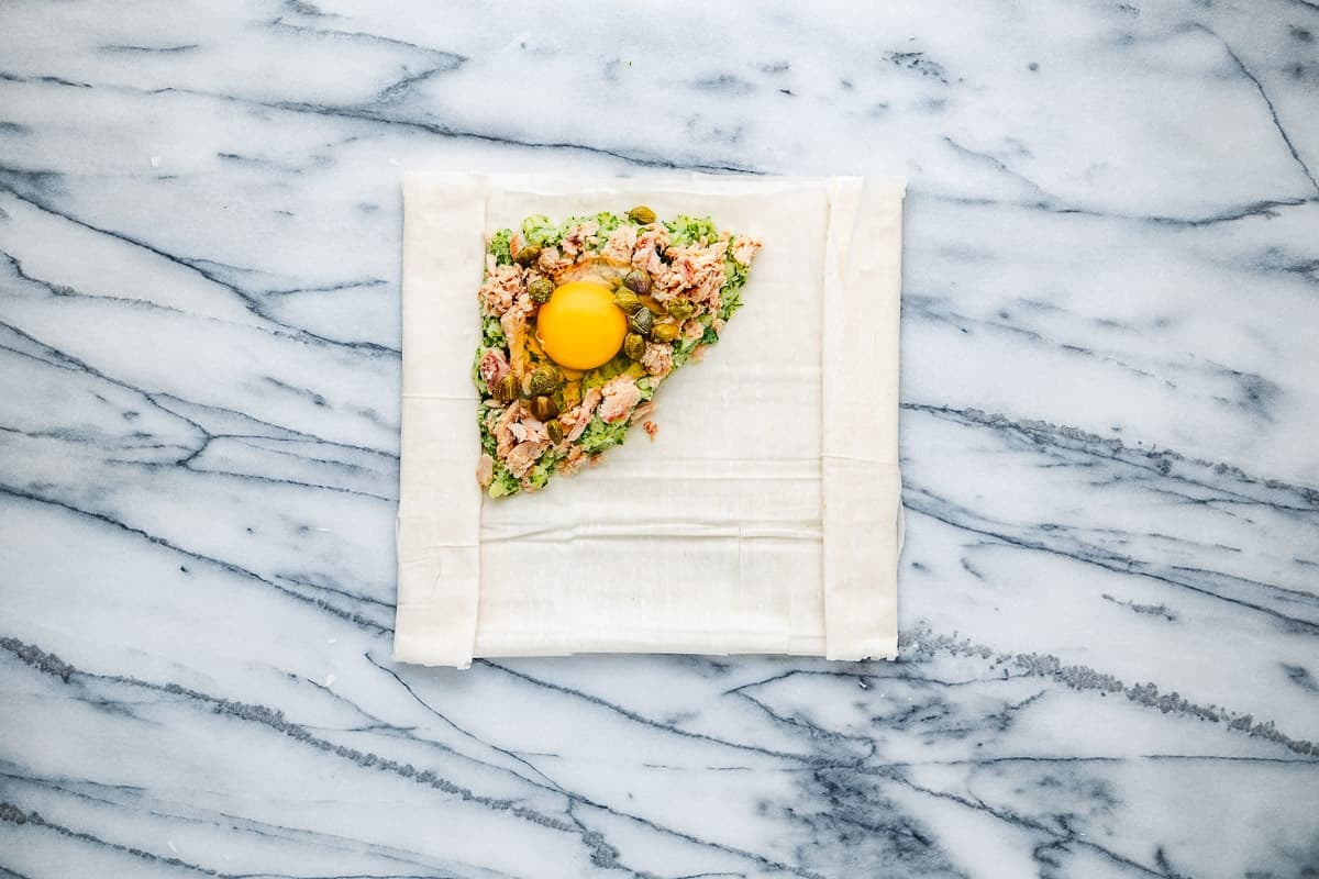 brik filling with an egg about to be folded into a square of filo dough.