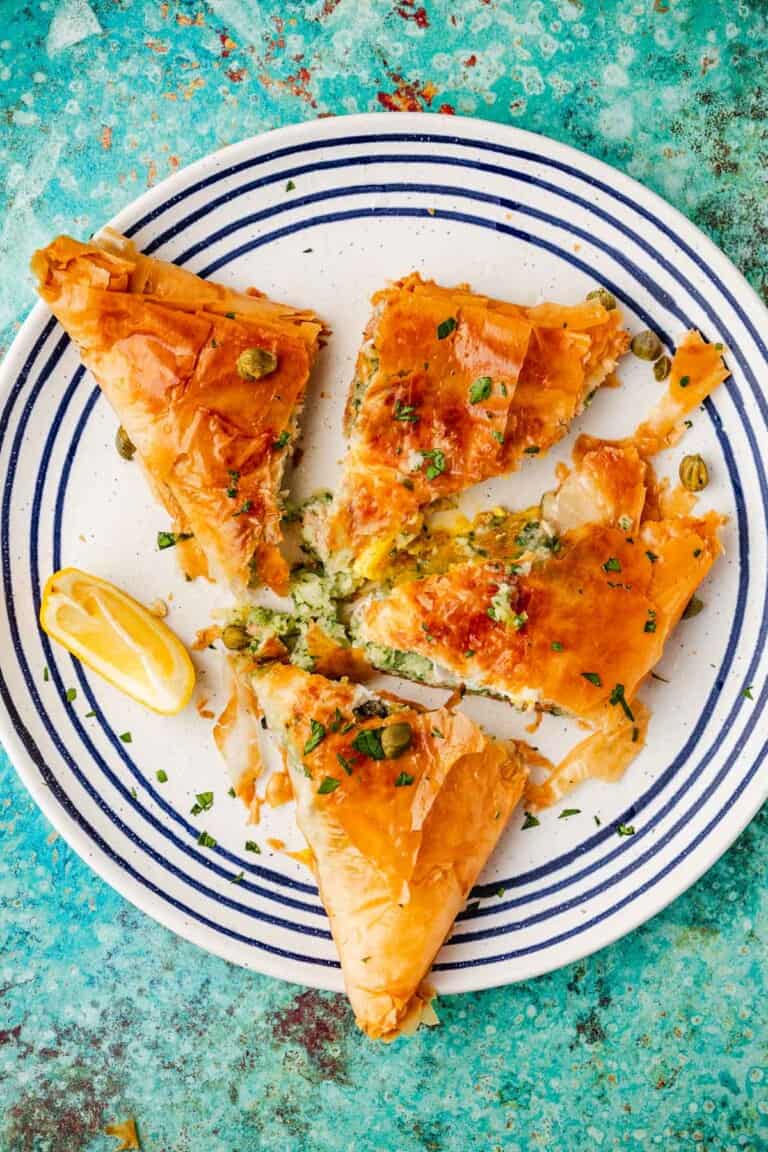 three pieces of brik on a plate with a lemon wedge.