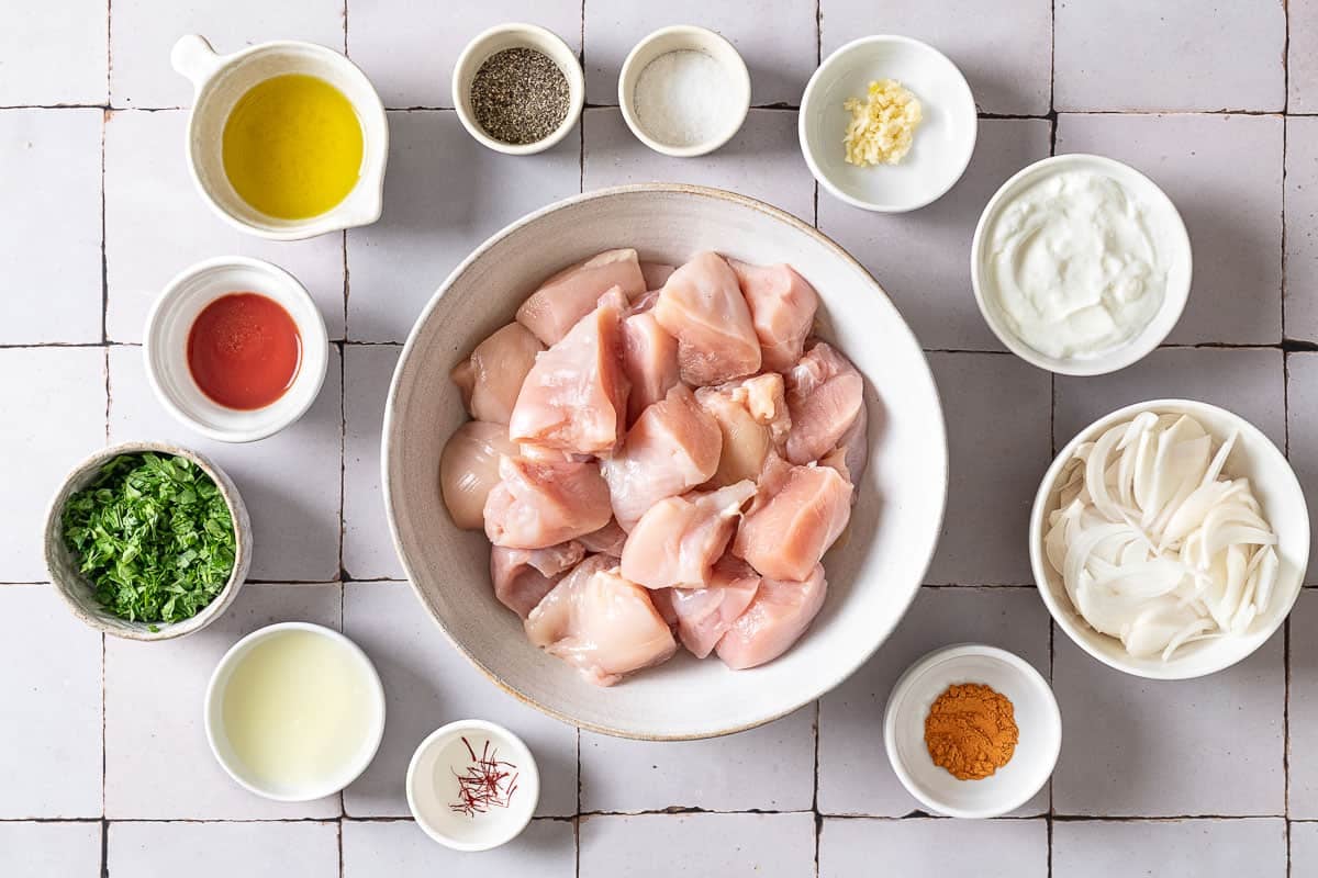 Ingredients for Joojeh kabob including chicken, saffron, onion, garlic, lemon juice, greek yogurt, olive oil, tomato paste, turmeric, salt, pepper and parsley.