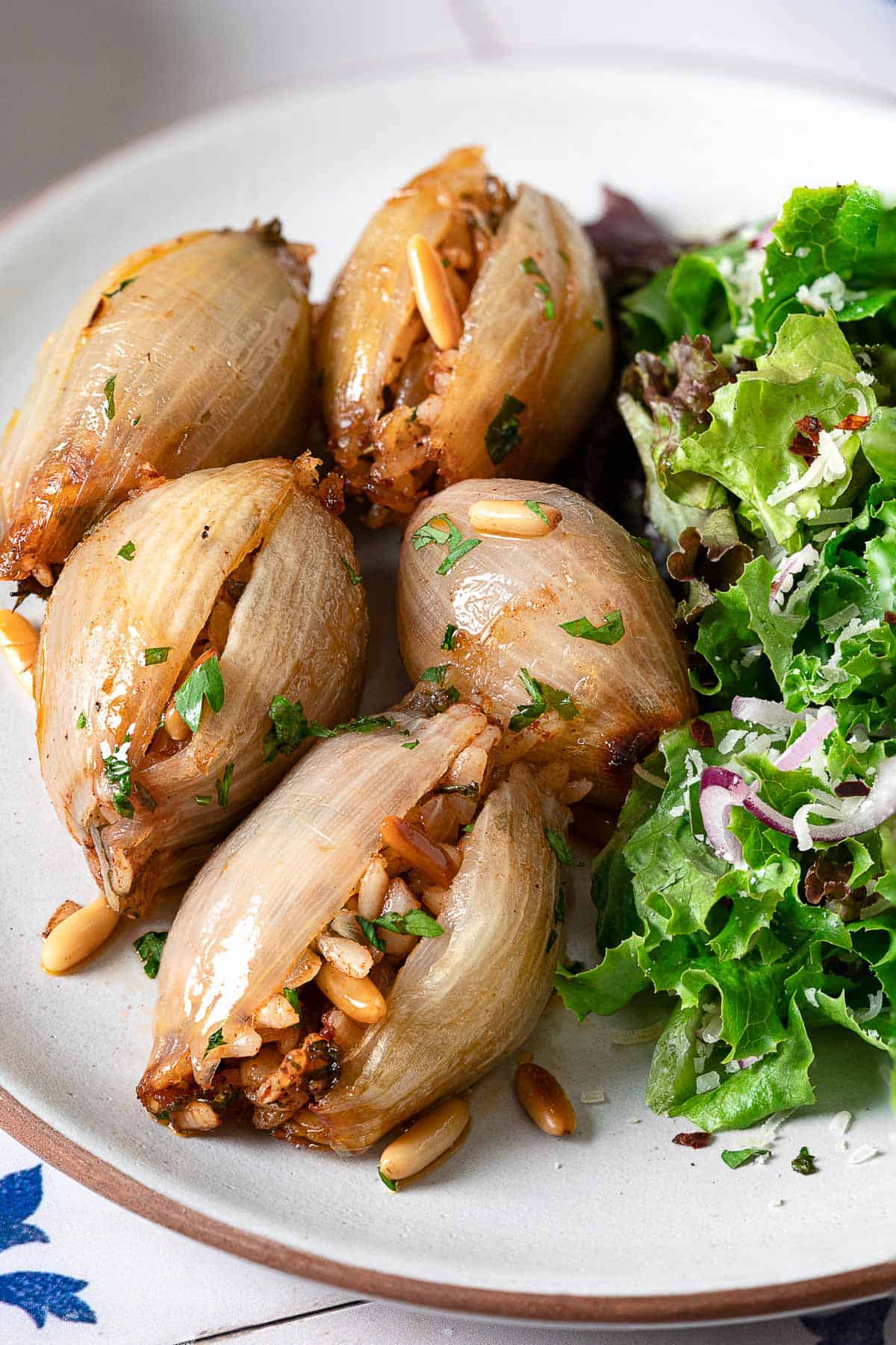 close up of stuffed onions on a plate with a side salad. 