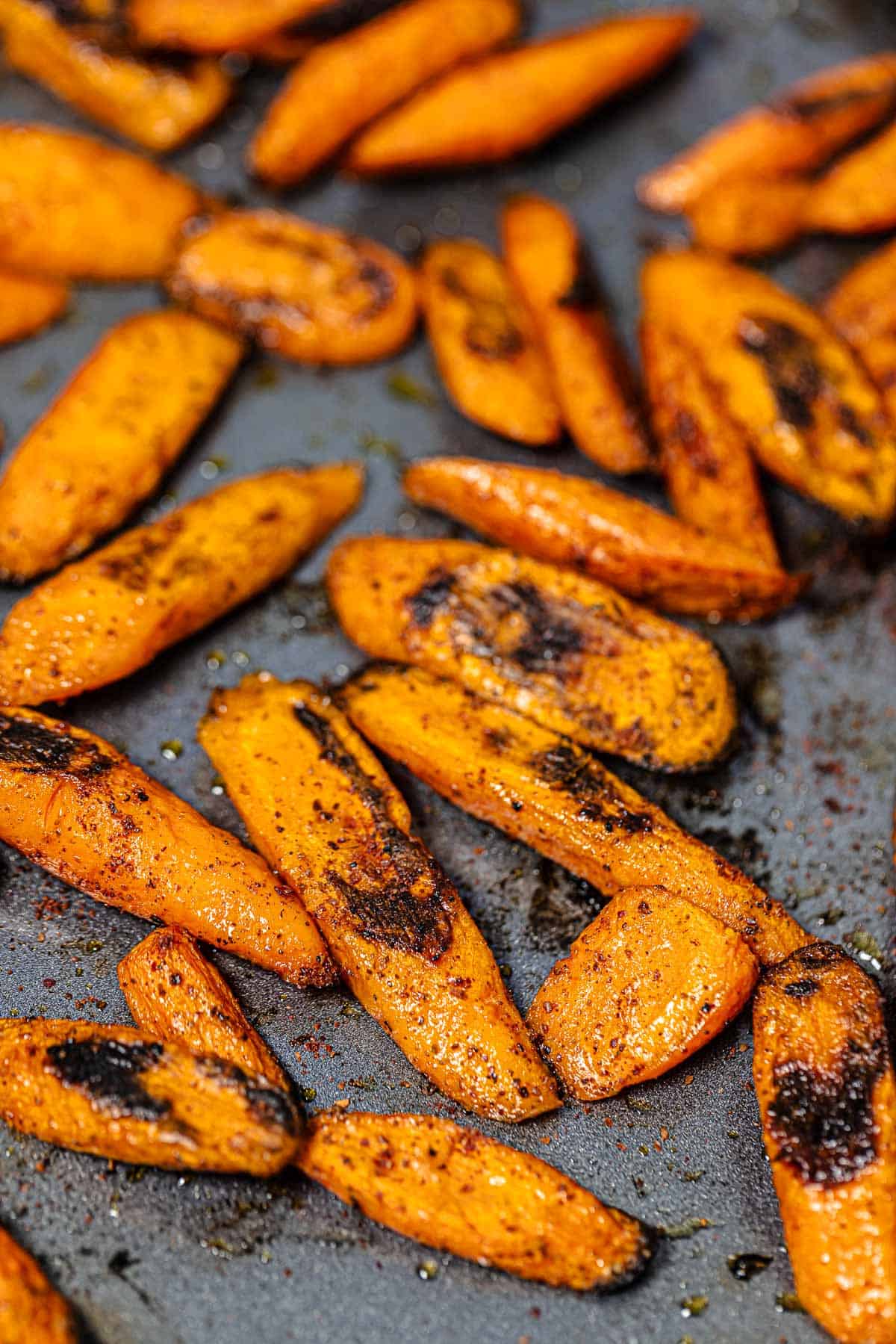 a close up of roasted carrots with sumac on a baking sheet.