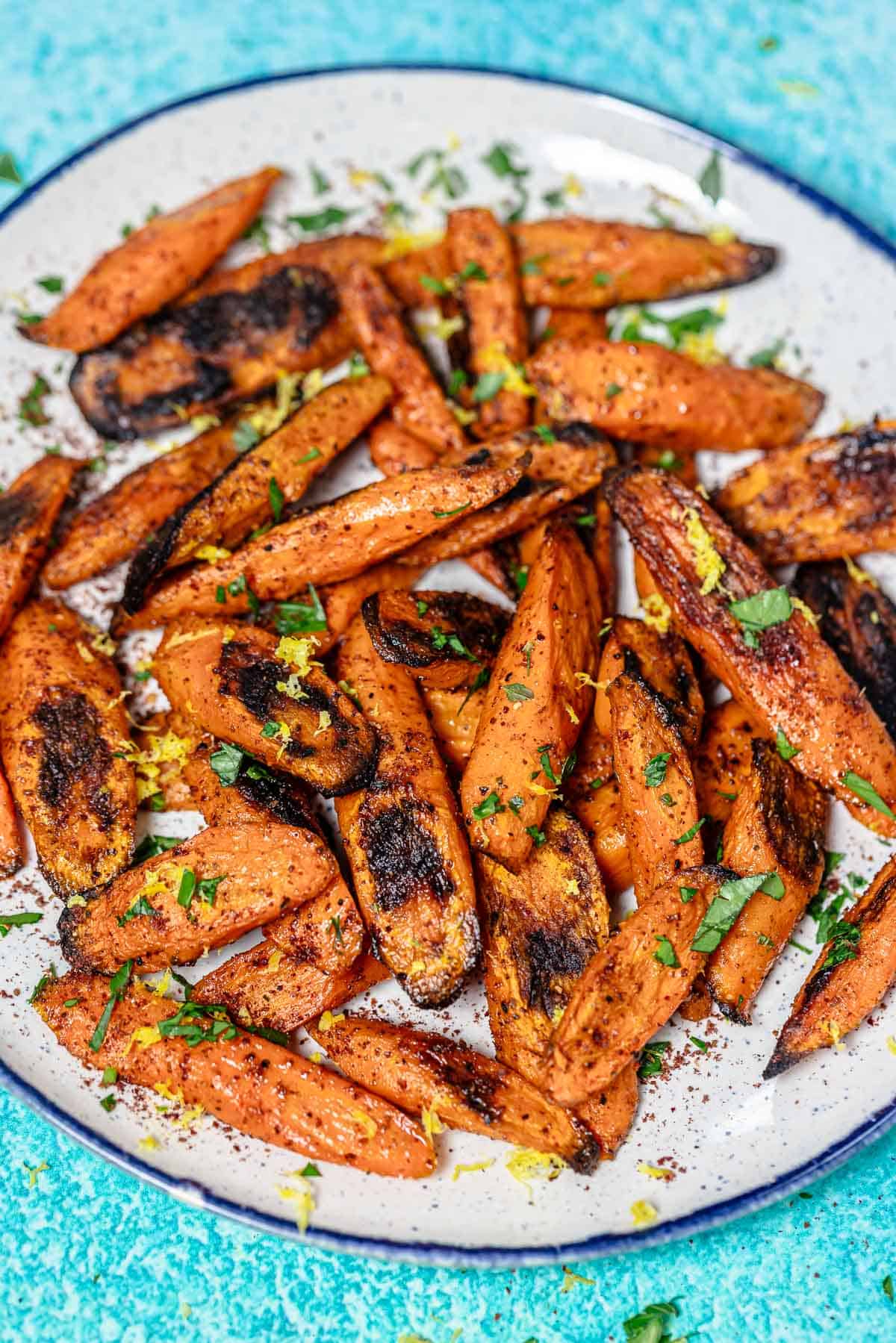 roasted carrots with sumac garnished with lemon zest and parsley on a serving plate.