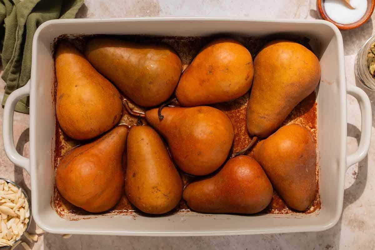Halved pears with the cut side down in a baking dish.