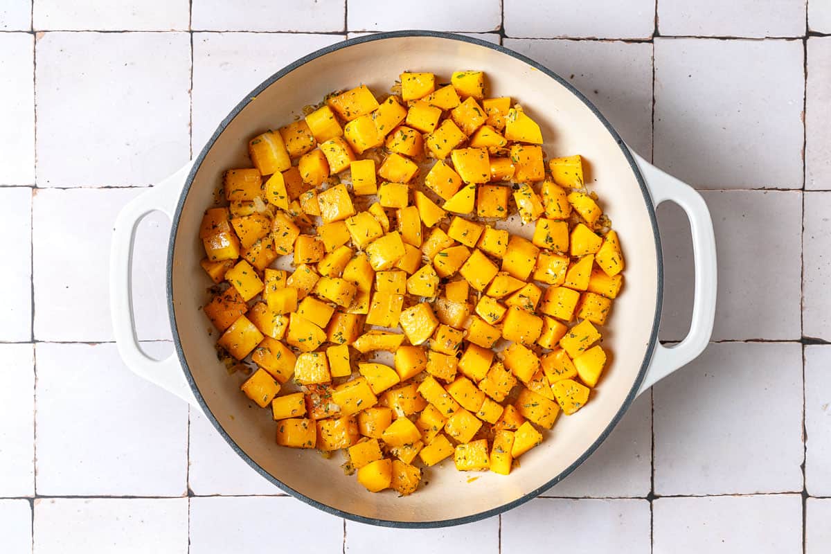 cubes of seasoned butternut squash simmering in a pot.