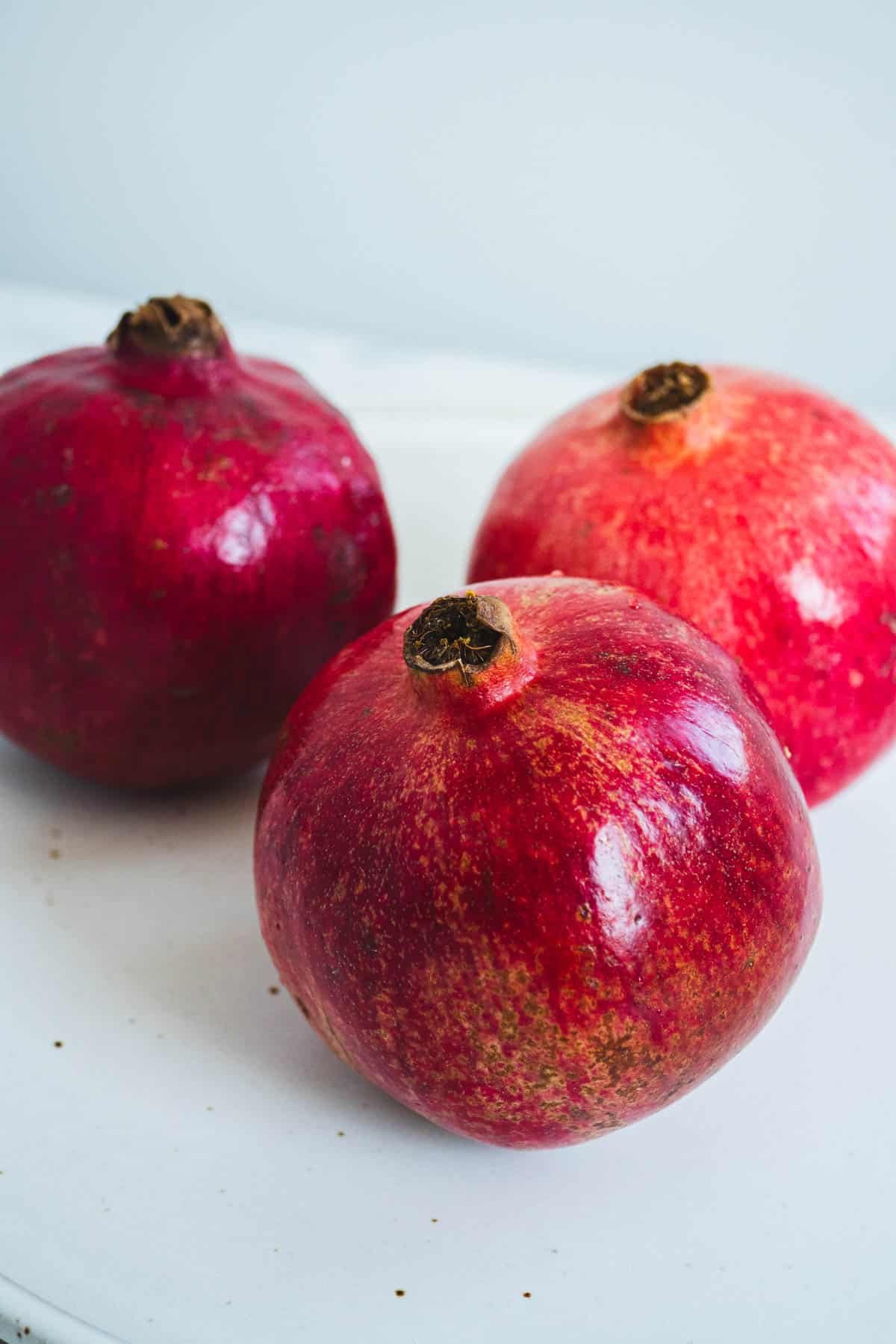 a close up of three whole pomegranates.