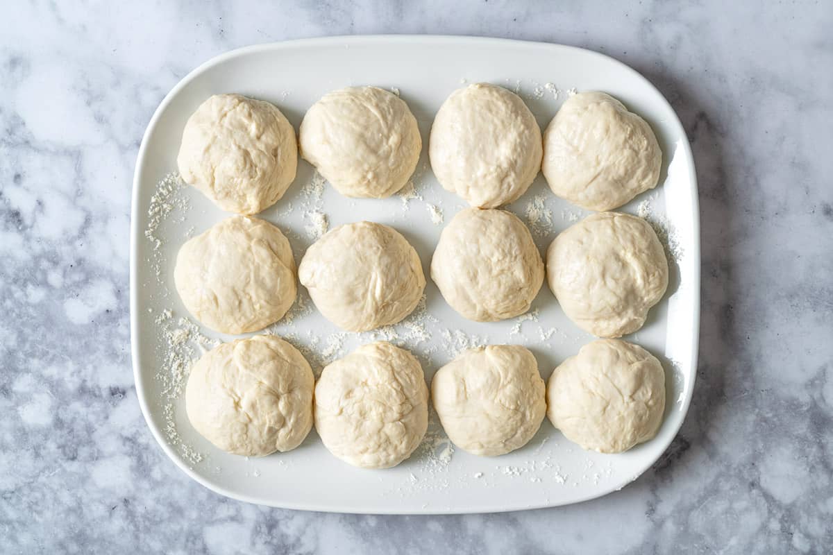 twelve portions of lavash bread on a white plate that has been dusted with flour.