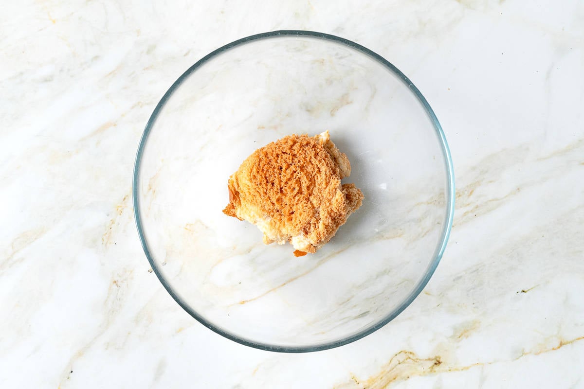 a soaked slice of bread in a clear mixing bowl.