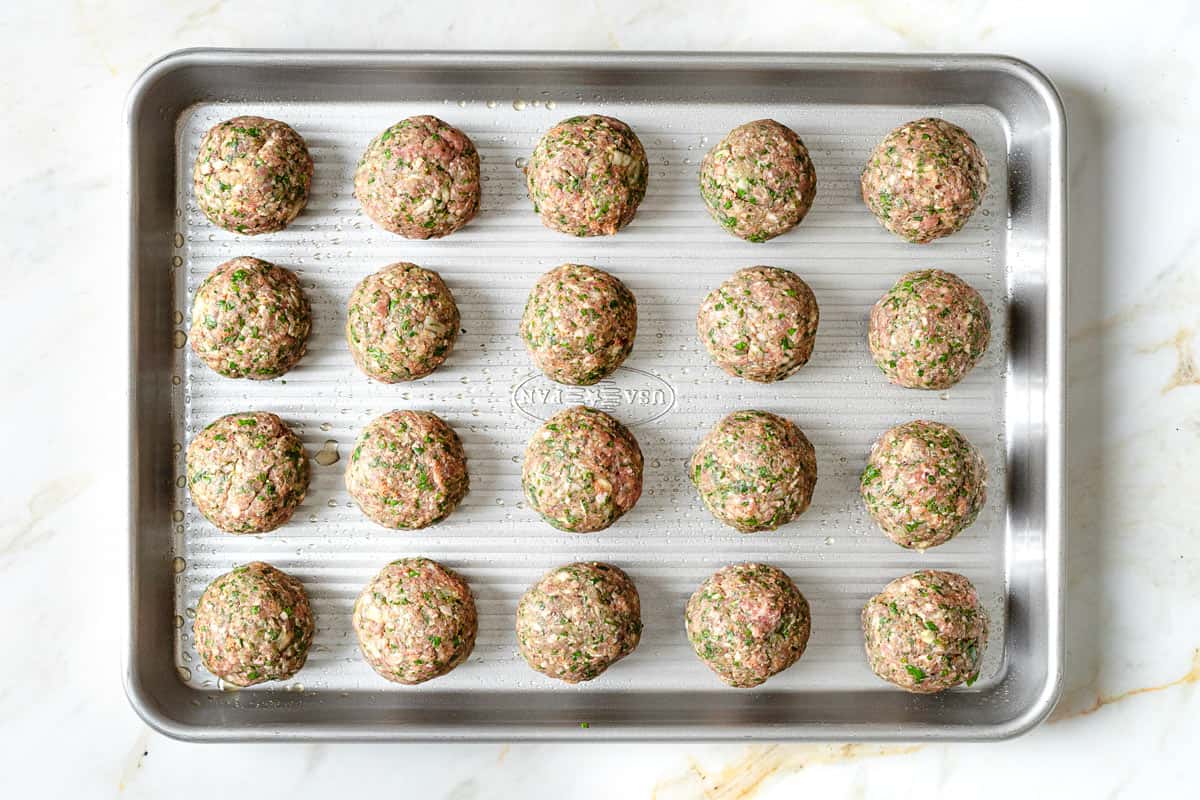 uncooked meatballs on a sheet pan.