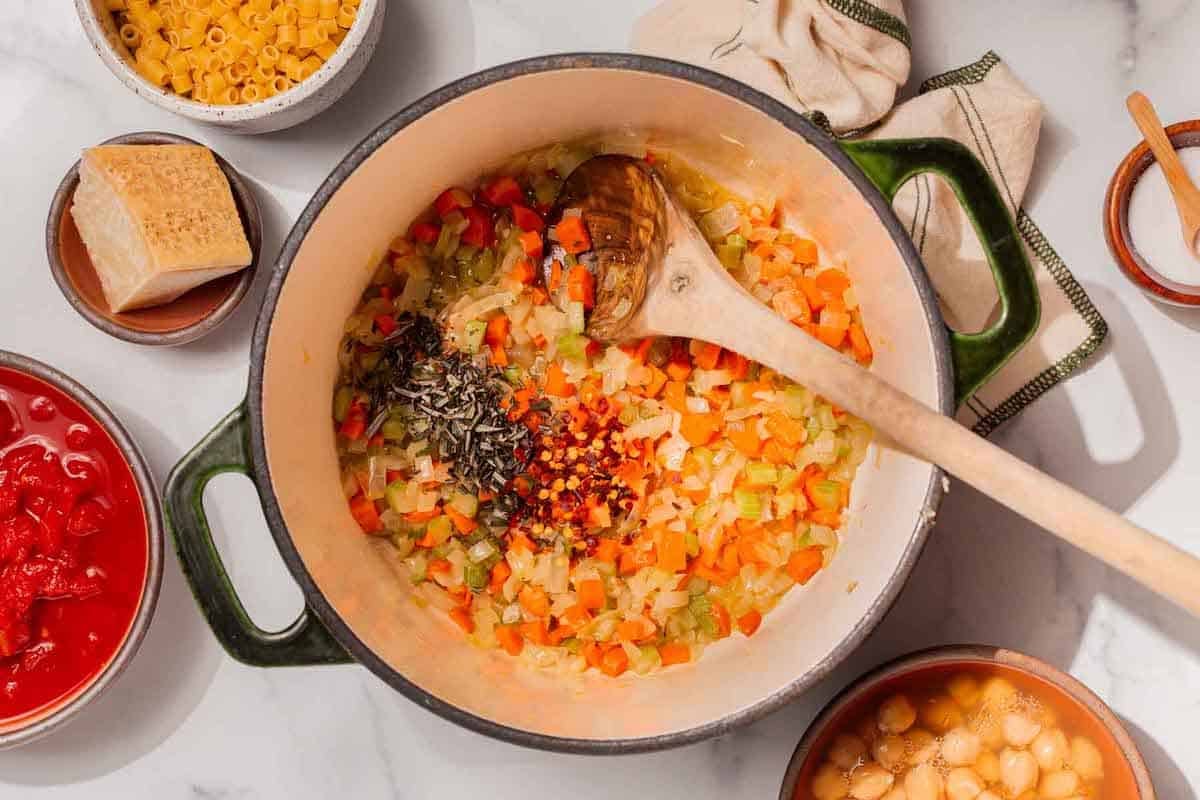 Carrot, onion, celery, red chili flakes, and rosemary in a pot.