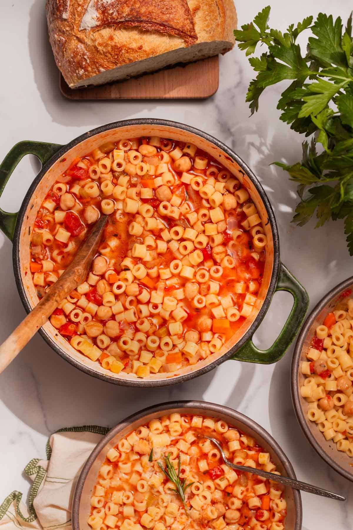 Overhead shot of a pot of pasta e ceci with a serving of pasta e ceci in a bowl.