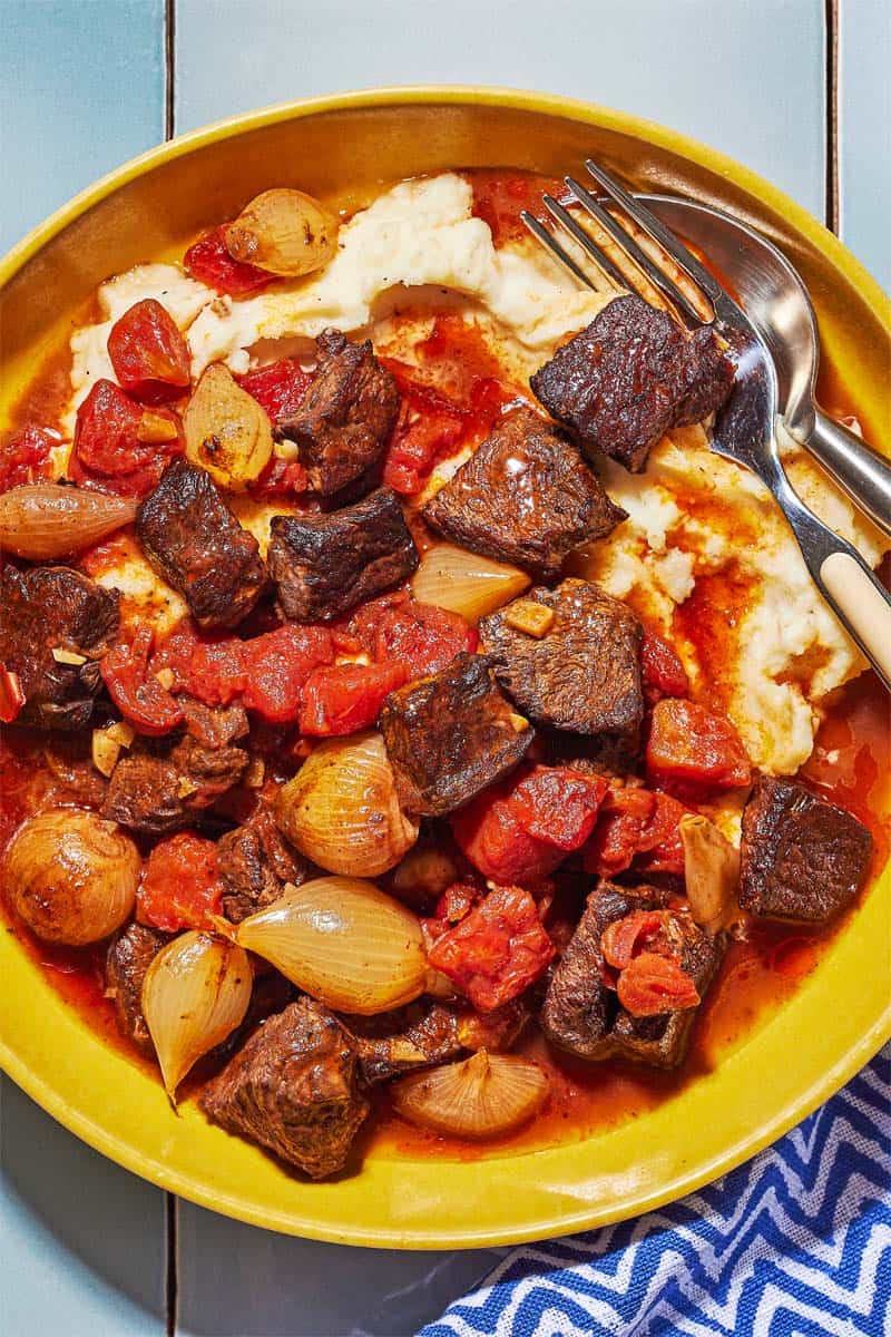 overhead shot of greek beef stew on top of mashed potatoes.