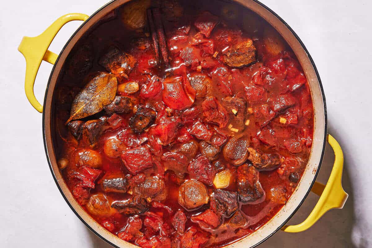 Greek beef stew in a pot. You can see the cinnamon stick and bay leaf.