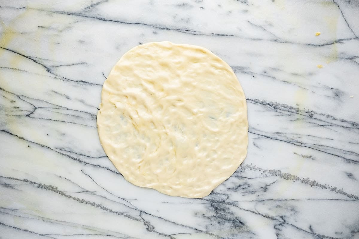 Mlewi flatbread dough starting to be stretched into a circle.