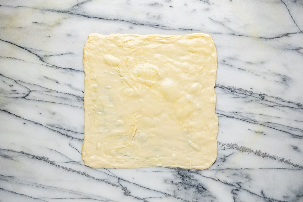 mlewi flatbread dough stretched into the shape of a square.