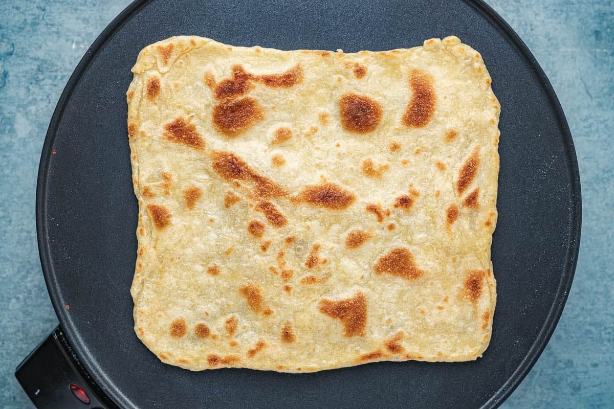 a close up of mlewi flatbread dough cooking on a hot plate.