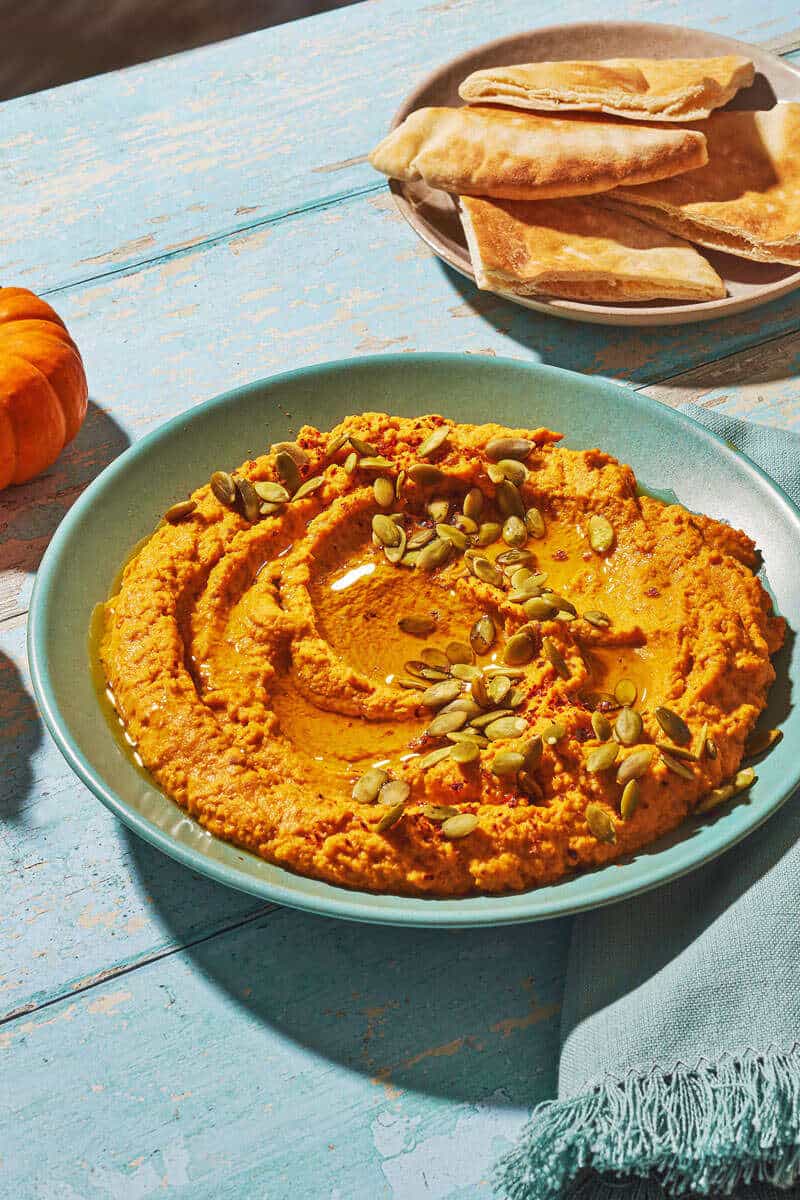 Side shot of pumpkin hummus, showing the drizzle of olive oil on top.