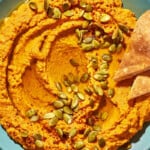 Overhead shot of pumpkin hummus with toasted pumpkin seeds and Aleppo pepper sprinkled over top.