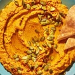 Overhead shot of pumpkin hummus with toasted pumpkin seeds and Aleppo pepper sprinkled over top.