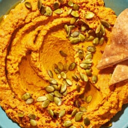 Overhead shot of pumpkin hummus with toasted pumpkin seeds and Aleppo pepper sprinkled over top.