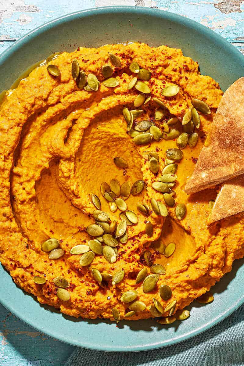 Overhead shot of pumpkin hummus with toasted pumpkin seeds and Aleppo pepper sprinkled over top.