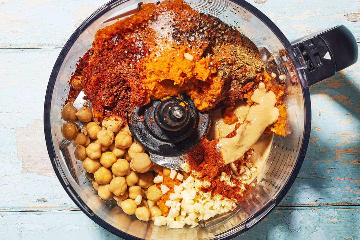 Garlic, tahini, pumpkin puree, chickpeas, and seasonings in a food processor before being blended.