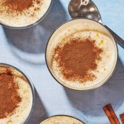 Overhead shot of four cups of Rizogalo, showing the generous amount of ground cinnamon on top.