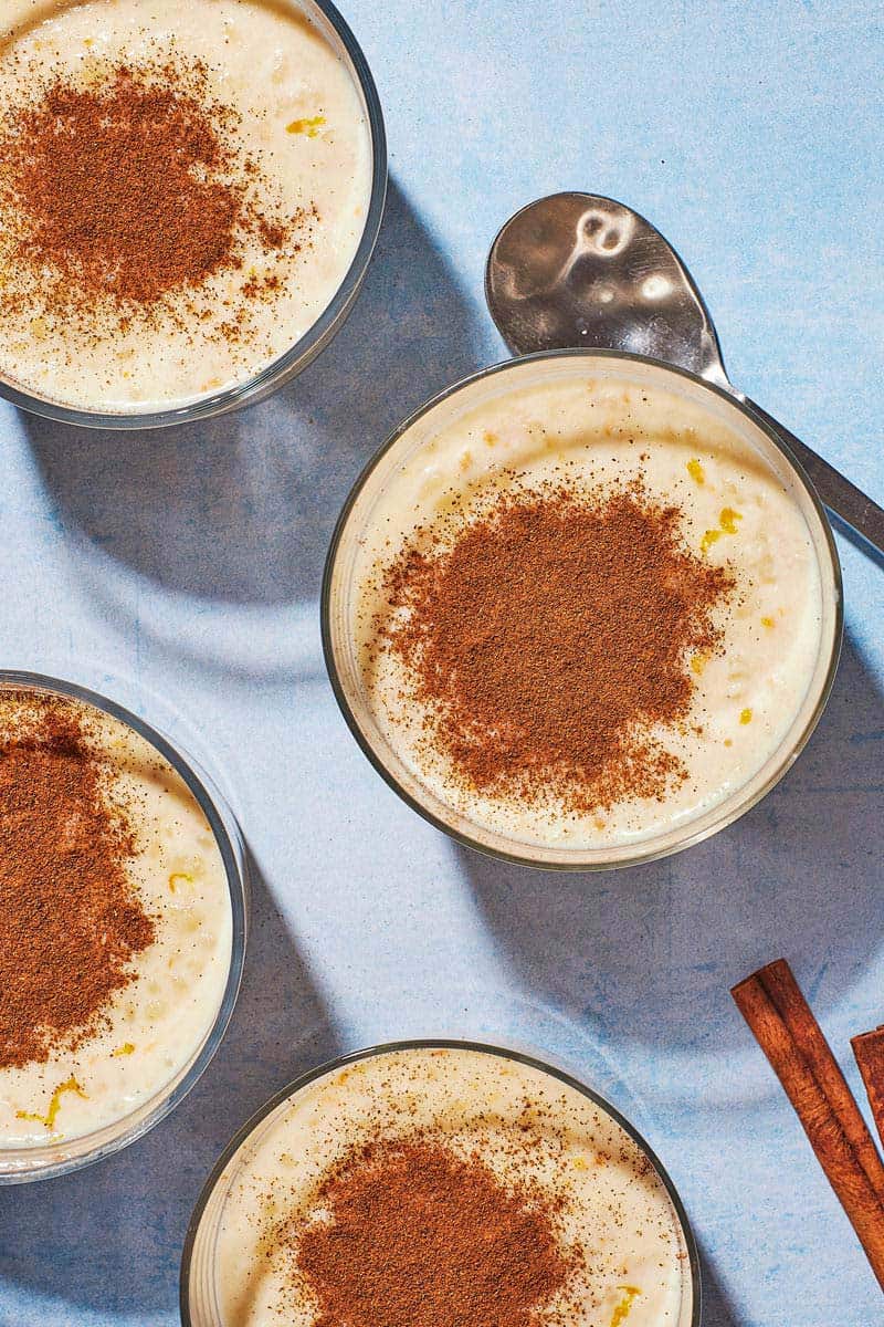 Overhead shot of four cups of Rizogalo, showing the generous amount of ground cinnamon on top.