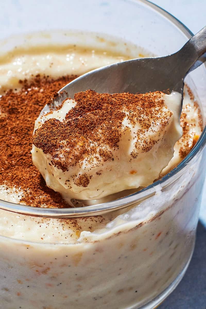 A spoon showing a scoop of Rizogalo, showing the plump rice and creamy texture and freshly ground cinnamon on top.