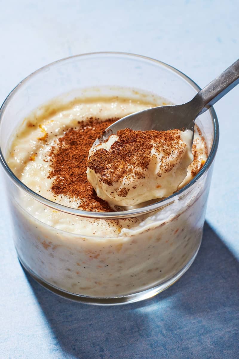 A spoon showing a scoop of Rizogalo, showing the thick and creamy texture and freshly ground cinnamon on top.