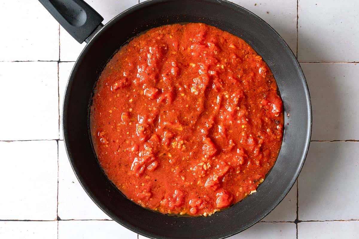 tomatoes simmering in a pan with spices and garlicky olive oil.