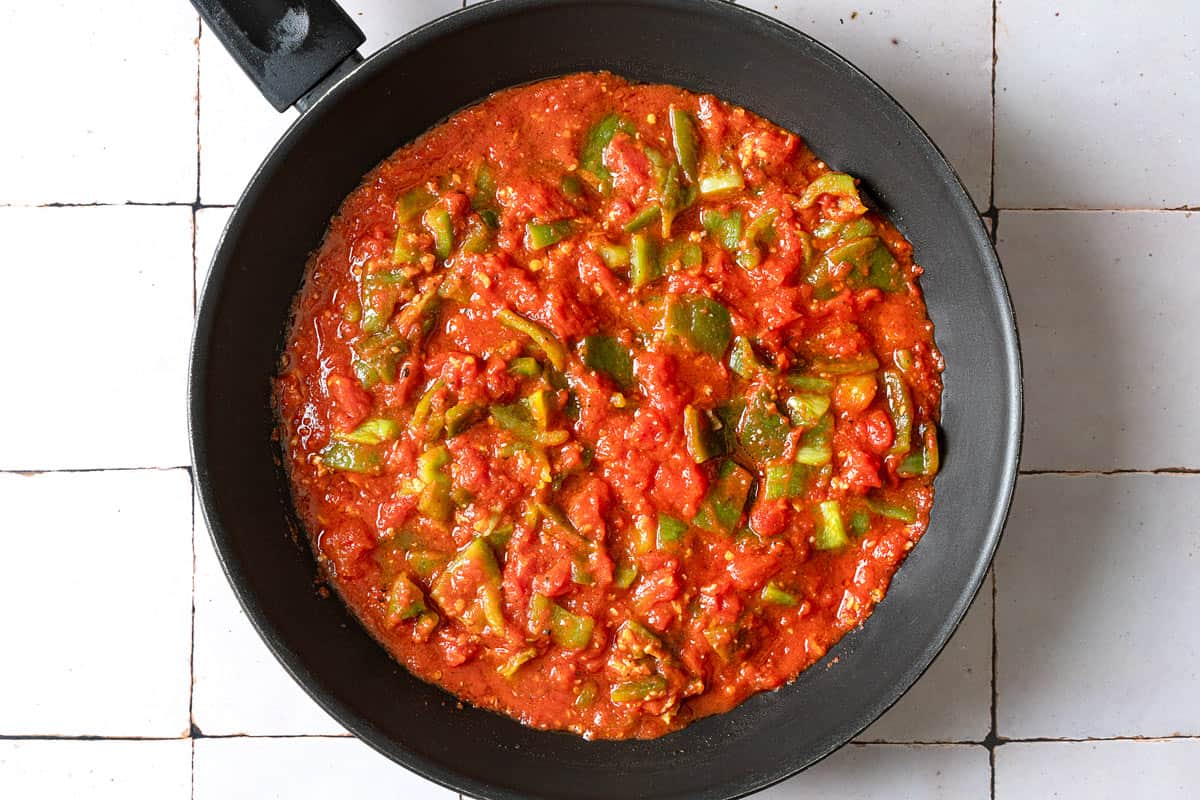 overhead shot of a pan with spiced tomato sauce and green bell pepper.