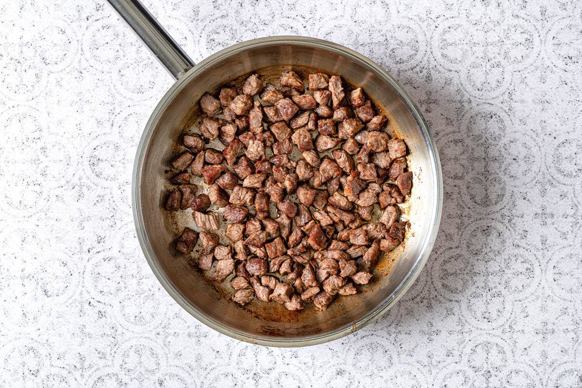 steak for tantuni being browned in a pan with oil.