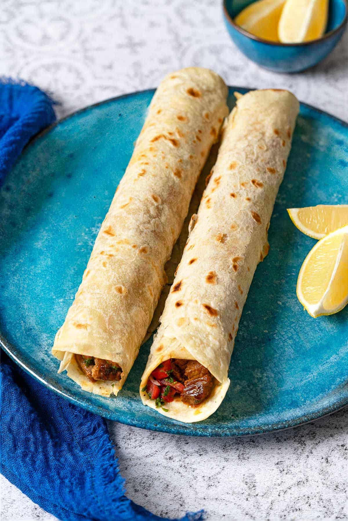 side shot of tantuni steak wraps showing the steak and tomato salad on the inside.