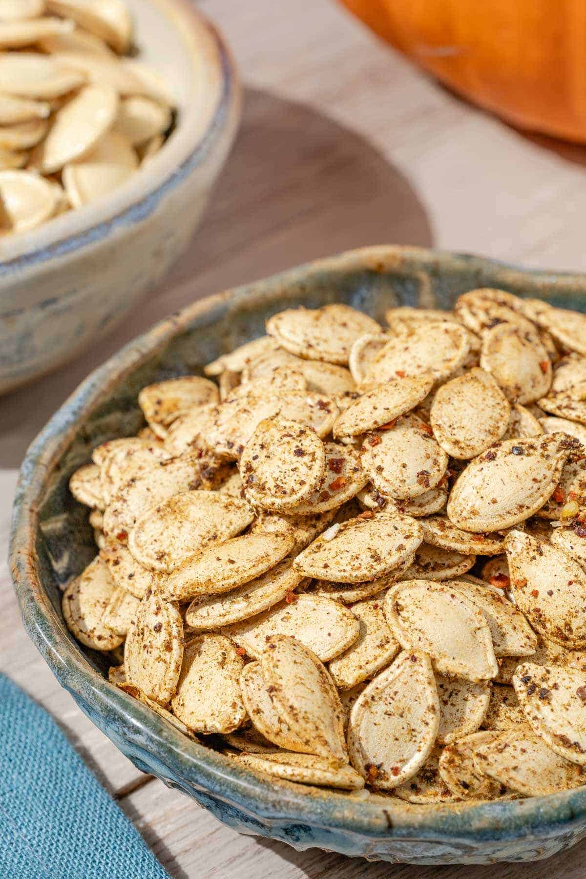 a close up of savory seasoned roast pumpkin seeds in a bowl.