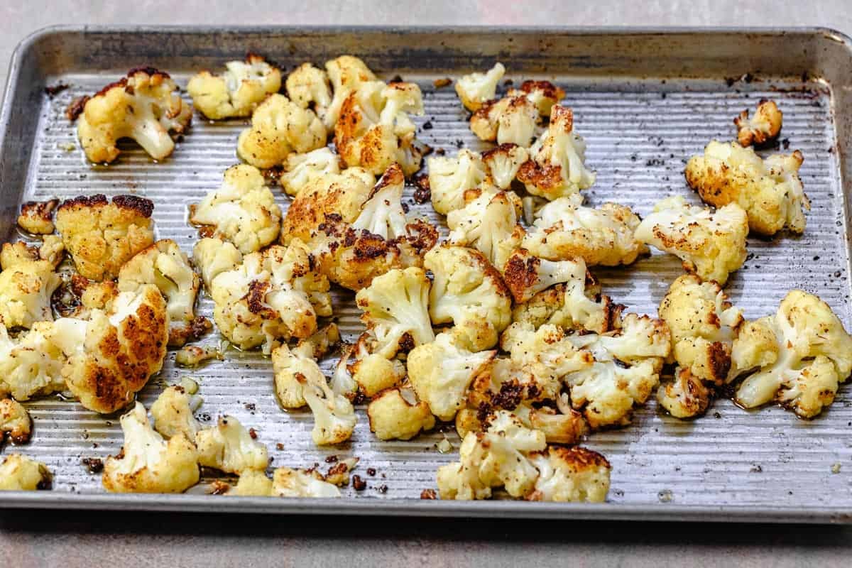 pieces of roasted cauliflower spread out on a sheet pan.