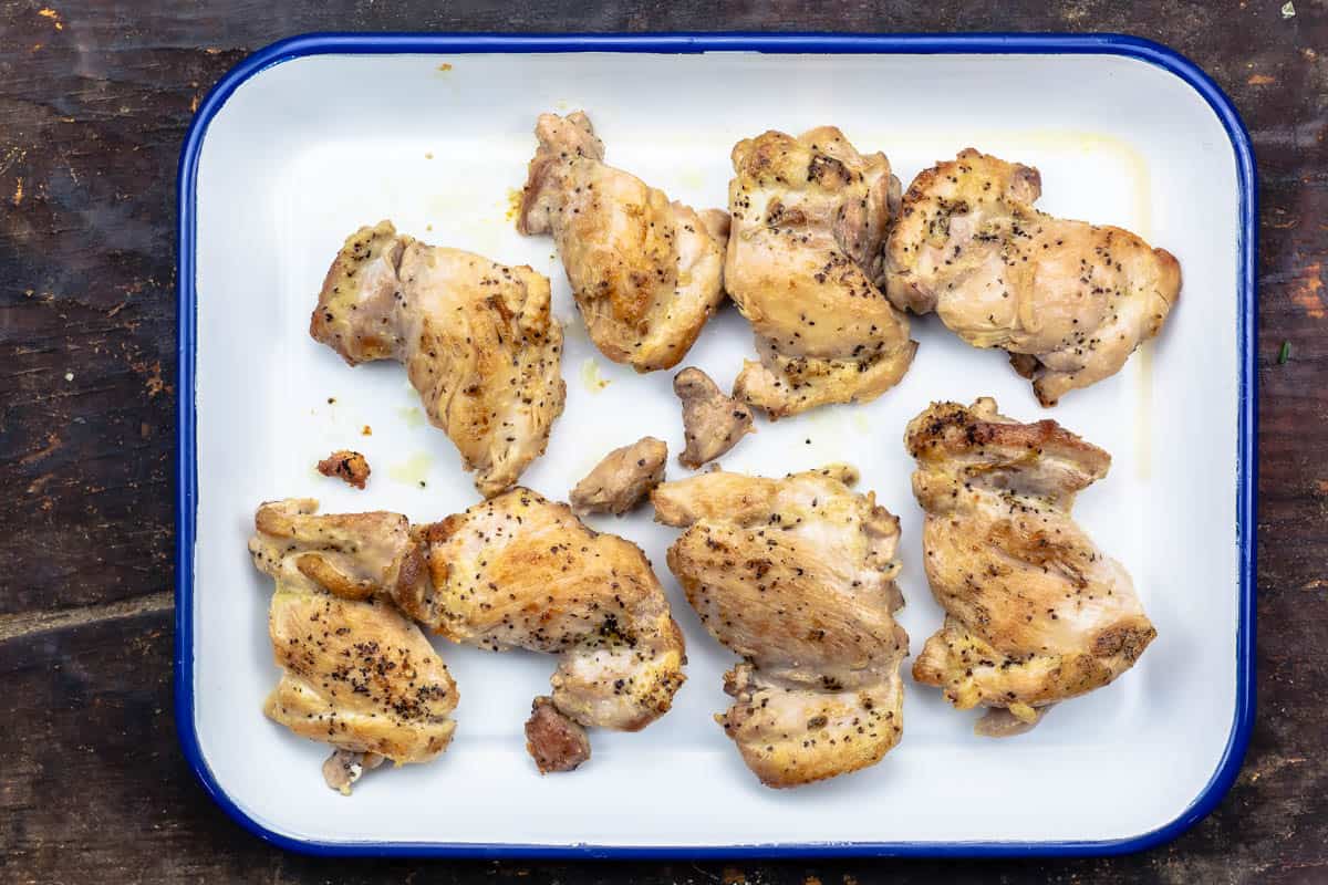 seasoned and cooked chicken thighs on a white serving platter.