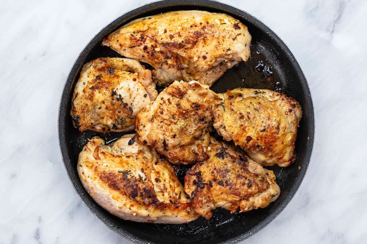 browned pieces of chicken in a skillet.