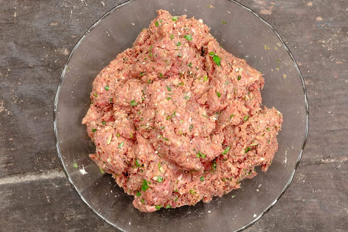 ingredients for the meatballs mixed together in a glass bowl.