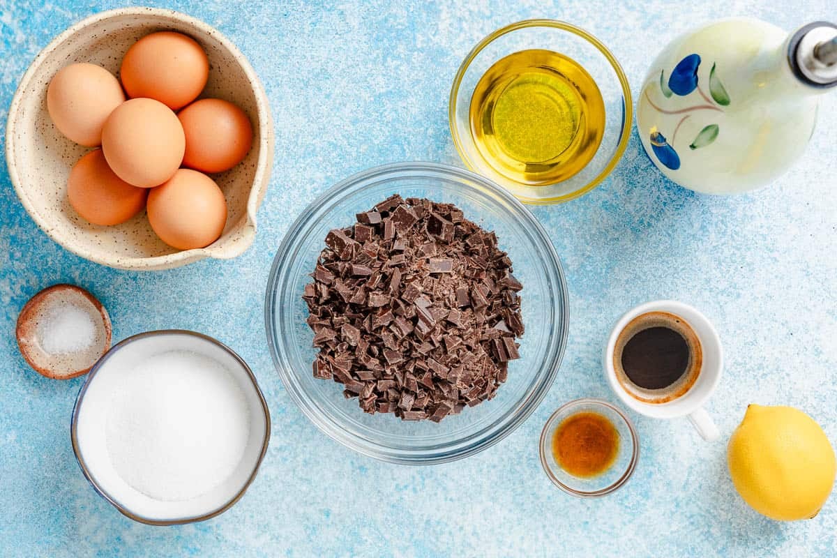 Ingredients for chocolate mousse, including chocolate, olive oil, eggs, salt, sugar, vanilla extract, espresso, and lemon.