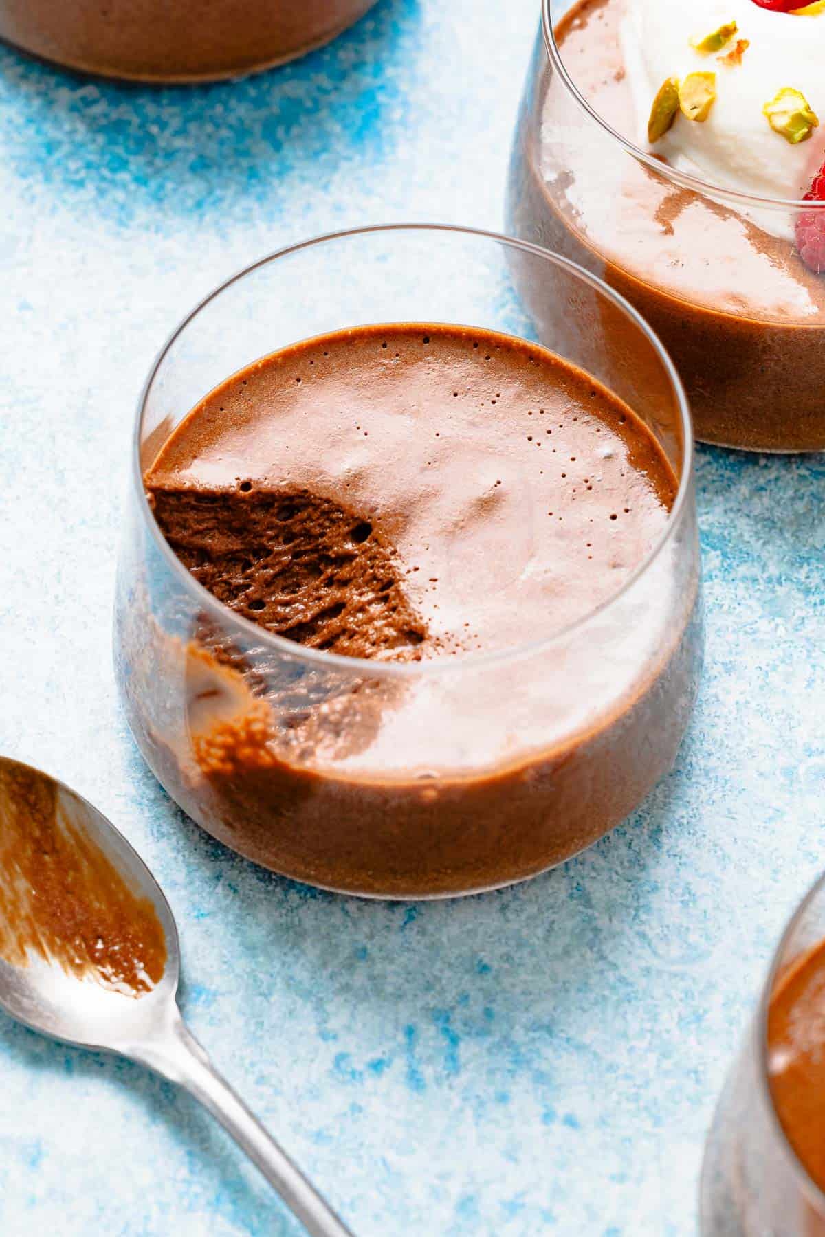 Overhead shot of a glass of chocolate mousse with a bite taken out, showing the airy texture.