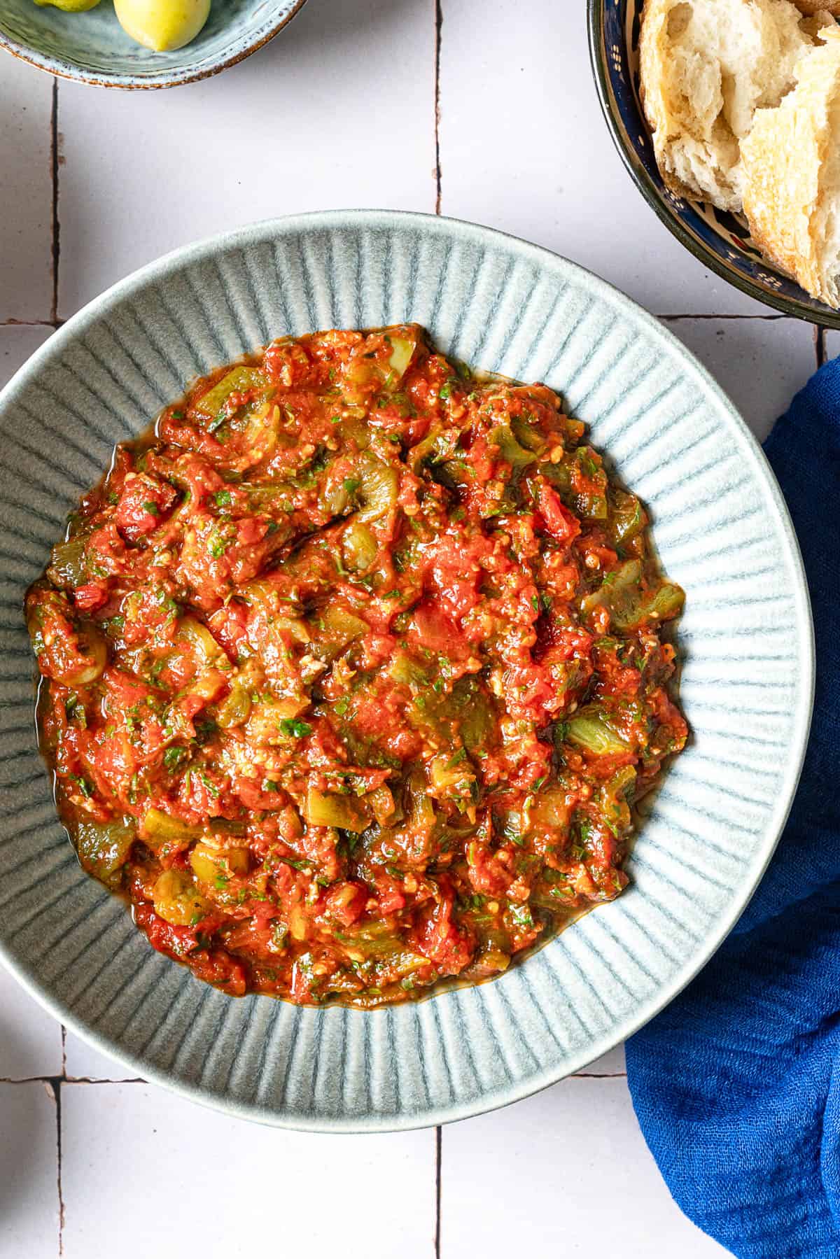 Overhead shot of taktouka in a blue bowl with bread on the side.