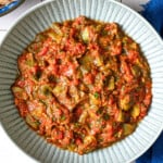 Overhead shot of taktouka in a blue bowl, showing the jammy tomatoes and oil around the edges.