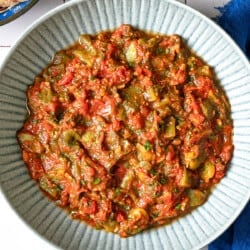 Overhead shot of taktouka in a blue bowl, showing the jammy tomatoes and oil around the edges.