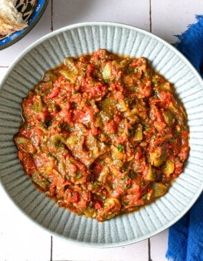 Overhead shot of taktouka in a blue bowl, showing the jammy tomatoes and oil around the edges.