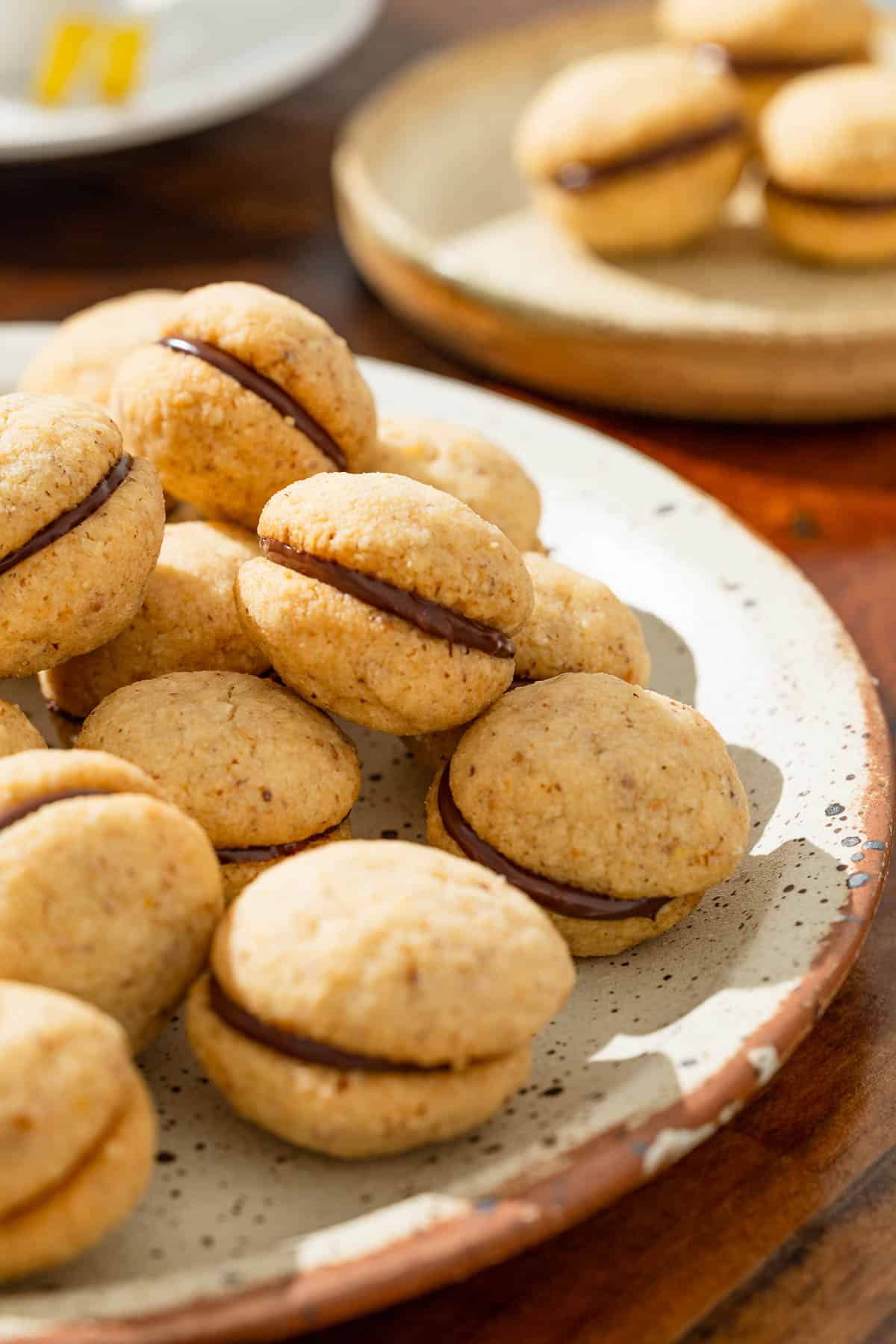 a close up of a serving plate with baci di dama hazelnut cookies next to a plate with three cookies.
