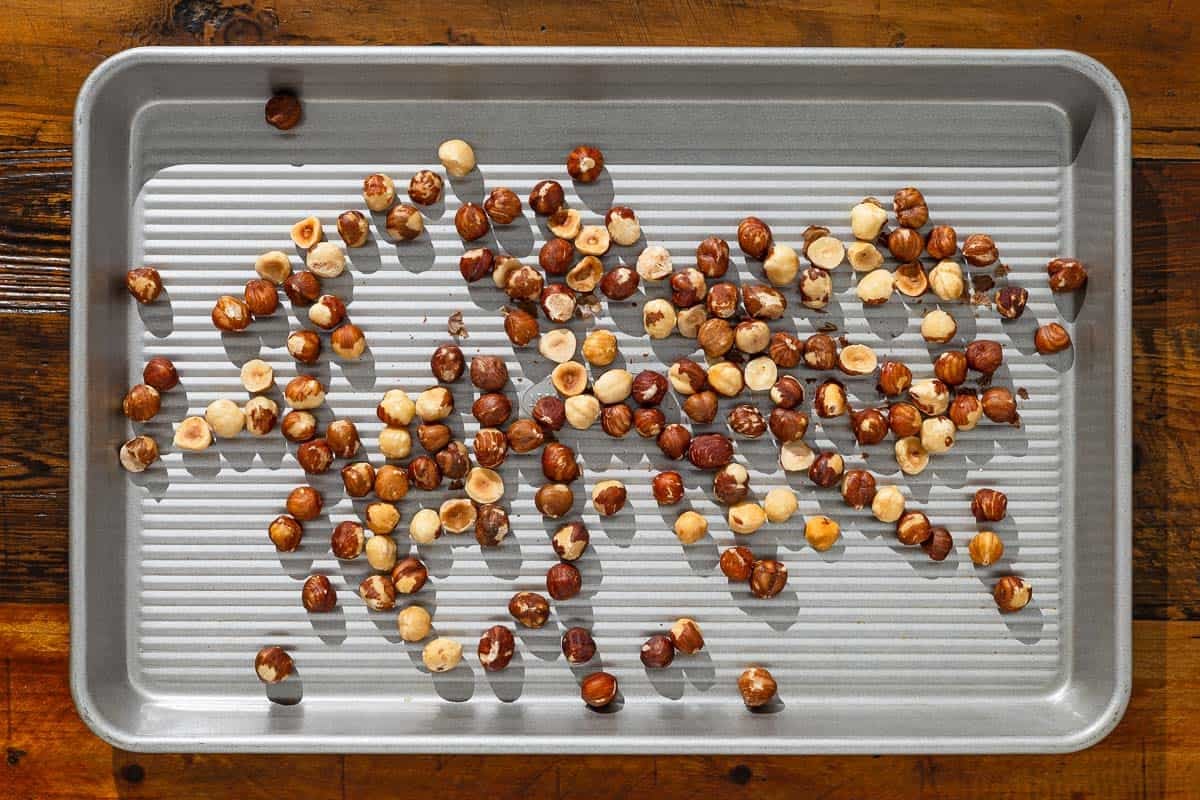 toasted hazelnuts spread out on a baking sheet.