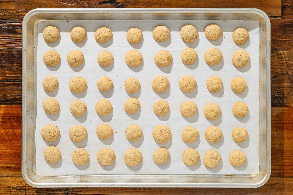 baked baci di dama hazelnut cookies spread out on a parchment lined baking sheet.