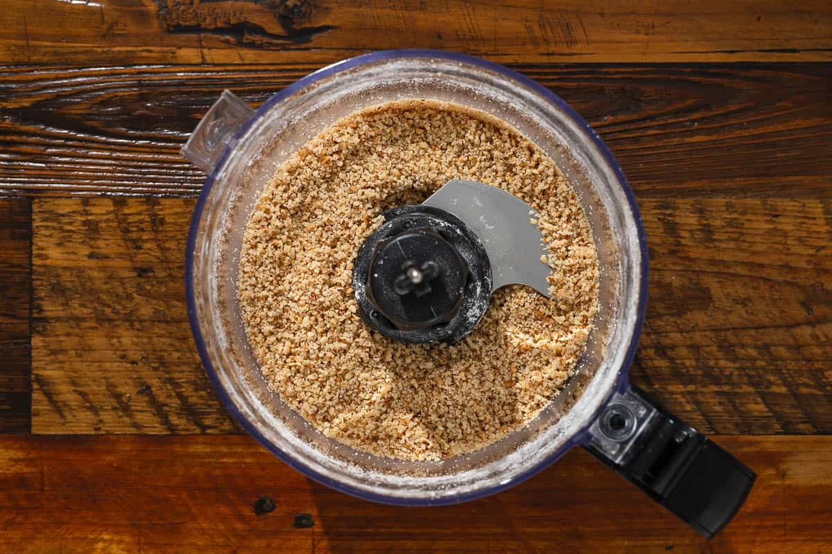 hazelnuts and powdered sugar in the bowl of a food processor after grinding.