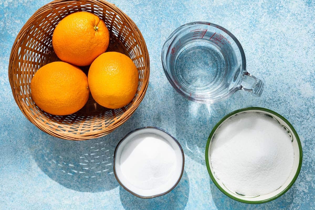 ingredients for candied orange peel including oranges, granulated sugar, superfine sugar and water.