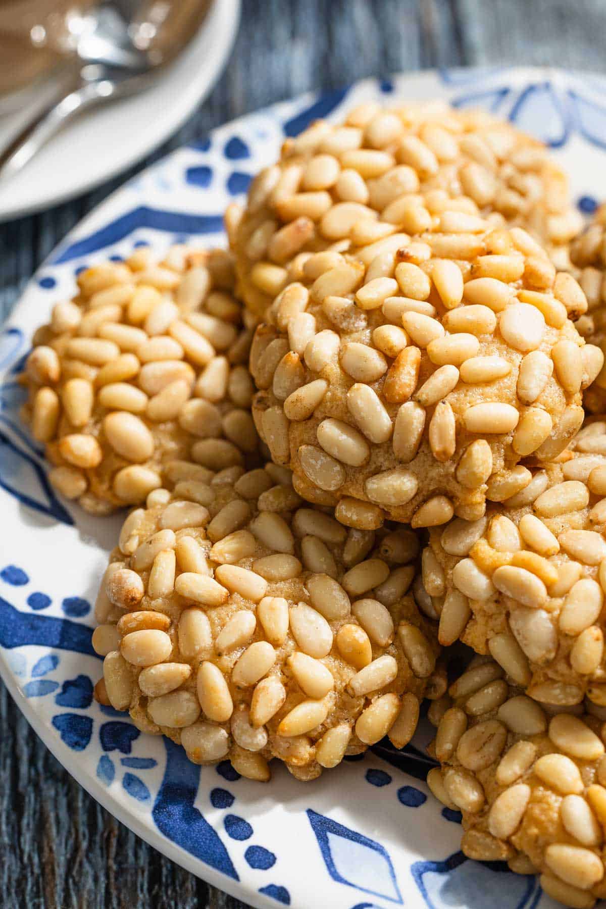 a close up of several pignoli cookies stacked on a serving plate.